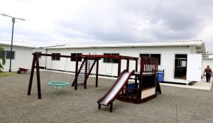 A white portable classroom with a playground out front