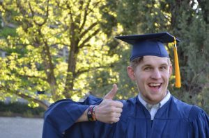 photo of a man graduating with a thumbs up
